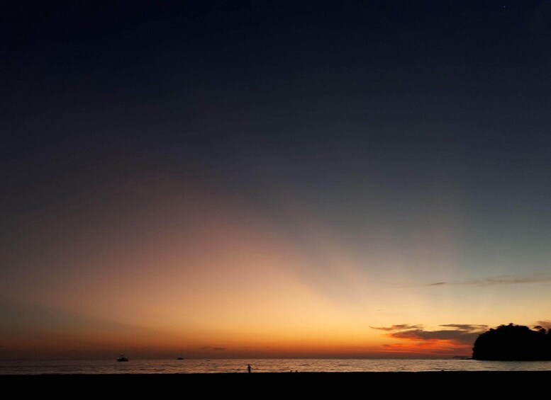 A sunset over the ocean with a silhouette of a landmass and a boat. 4