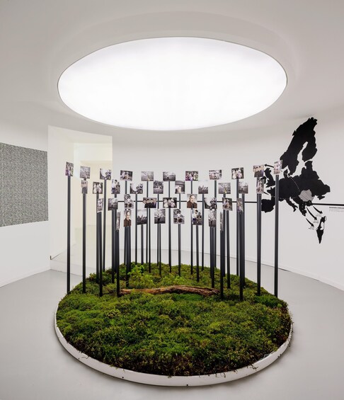 A circular exhibit with photos on poles, a map, and a mossy base. 3