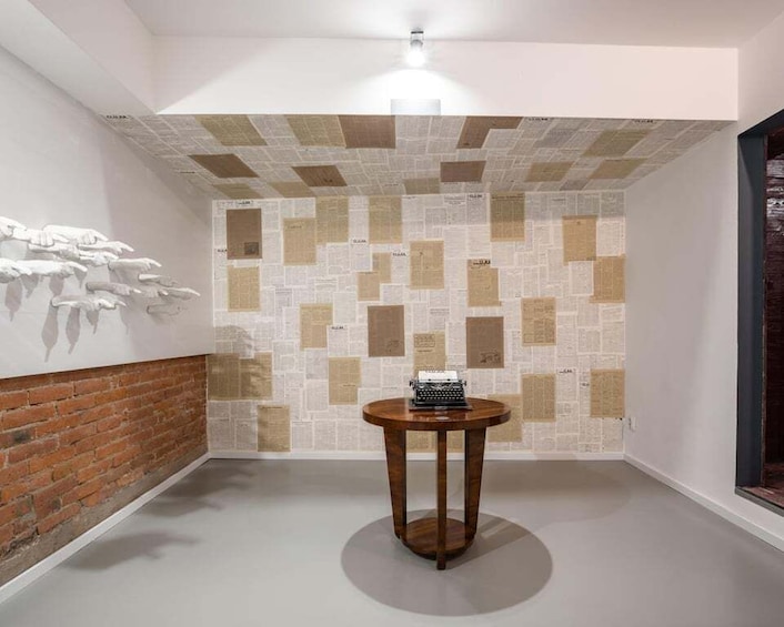 A room with a patterned wall, a round wooden table, and a brick wall. 2