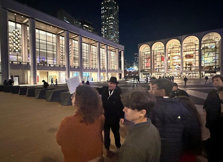 A nighttime urban square with modern buildings and a crowd of people. 5