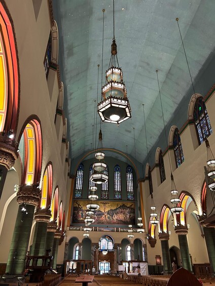 An interior with arched windows, a large chandelier, and a mural on the wall. 3