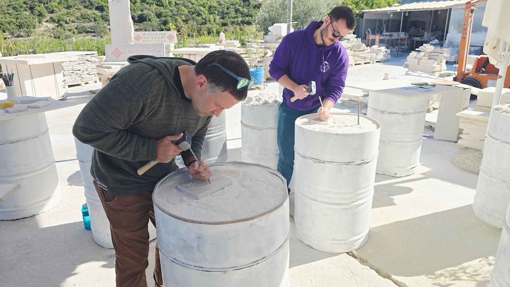 Two individuals working with large white barrels, possibly in a workshop or construction area with various tools and materials around. 4