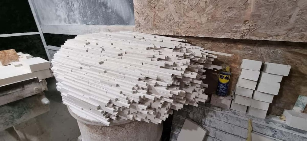 A large pile of white rectangular blocks, possibly construction materials, stacked on a concrete column. 3