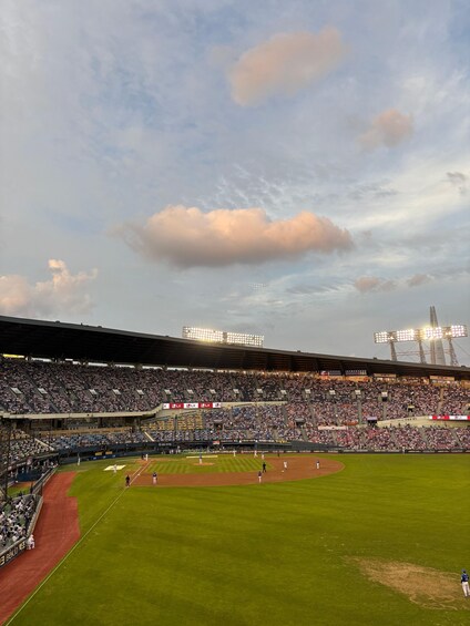 A baseball stadium with a large crowd, a baseball diamond, and floodlights. 4