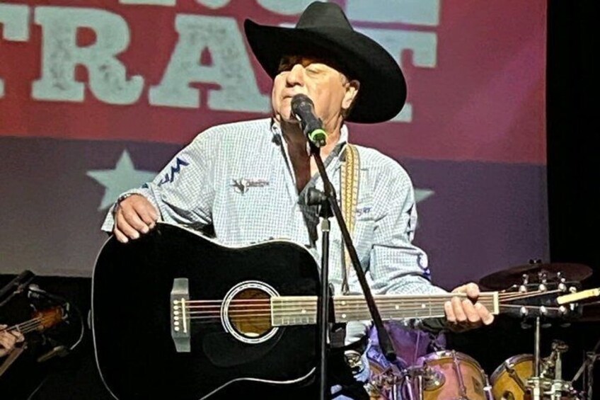 A person playing a guitar on stage with a microphone. 3