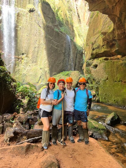 A group of hikers in a forested area with a waterfall in the background. 3
