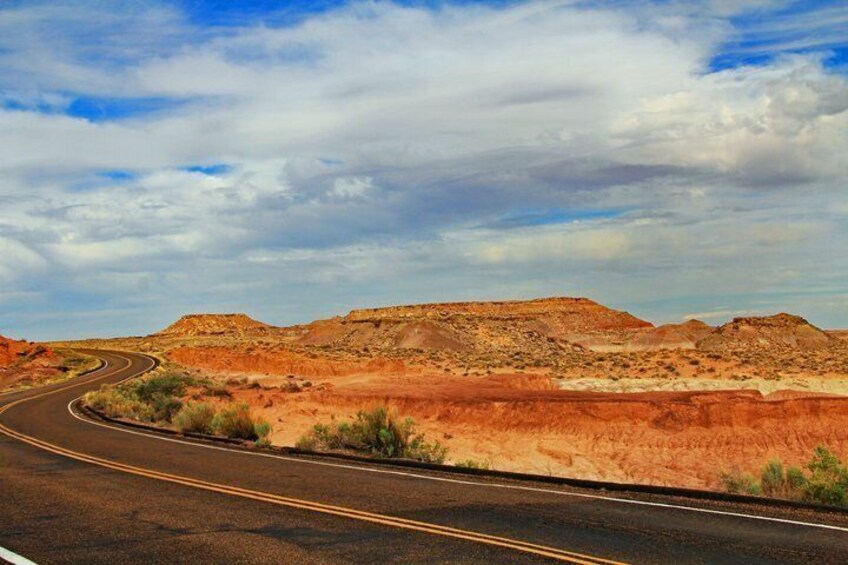 A winding road through a desert landscape with red rock formations. 3