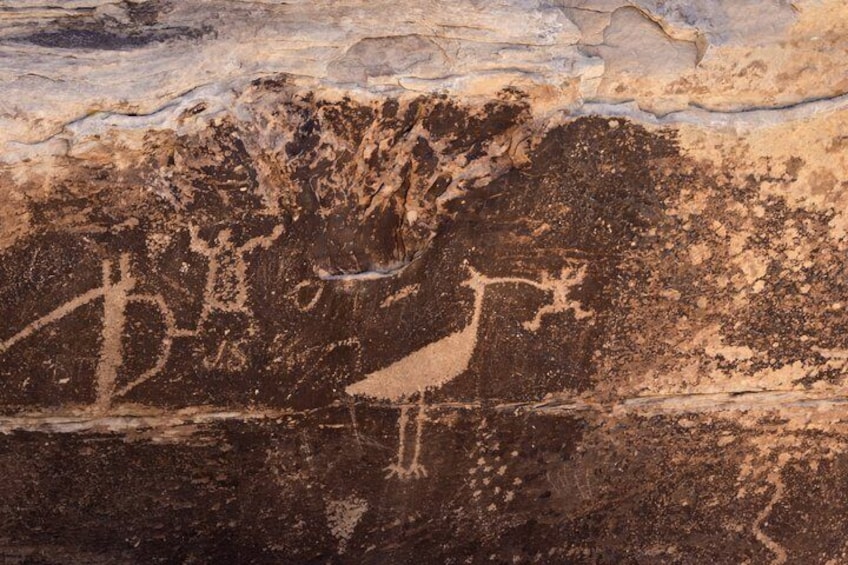 A rock surface with ancient petroglyphs depicting a human figure and a tree. 4