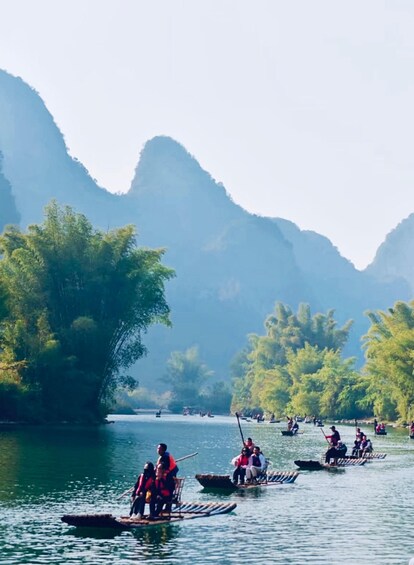 People paddling in canoes on a river surrounded by mountains. 1