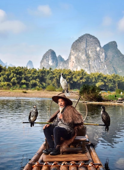 A person sitting on a bamboo raft with birds perched on a net. 2