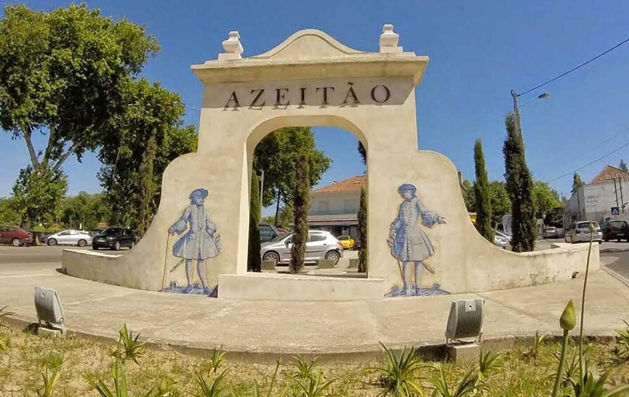 Monumentissa on kaiverrettu teksti »AZEITÃO», ja siinä on kaksi sinisiin vaatteisiin pukeutuneiden henkilöiden patsasta. 4