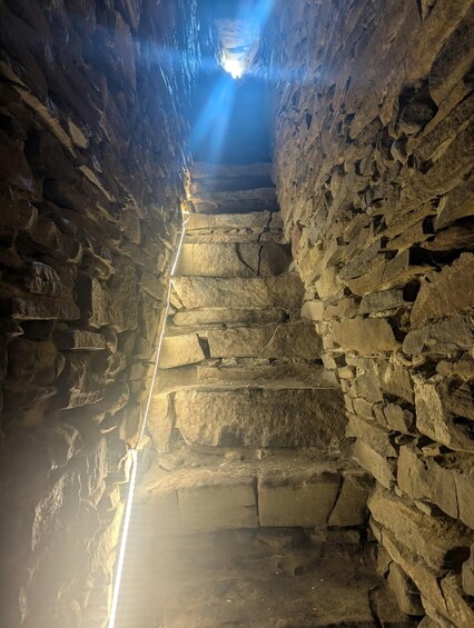 A narrow stone passageway with a light source at the end. 5