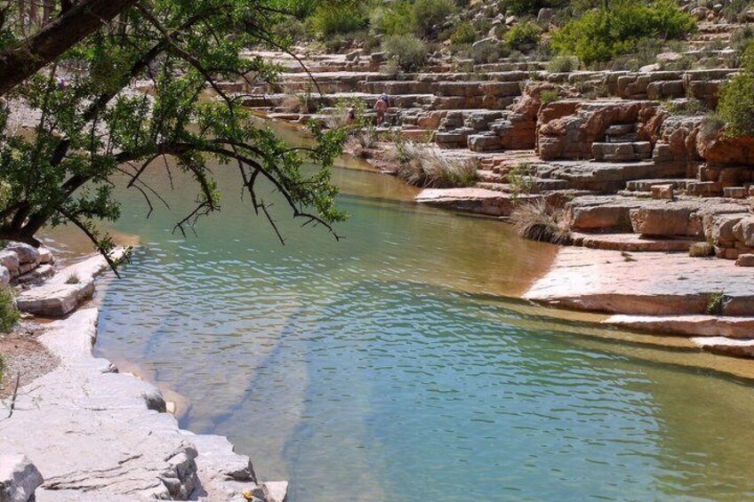 A clear river with rocky steps and sparse vegetation. 4