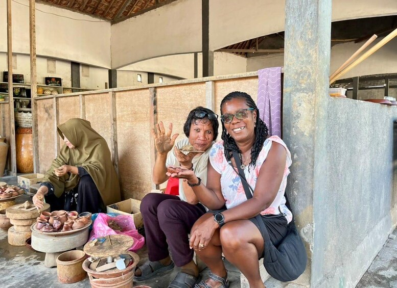 Trois personnes sont assises à l’extérieur d’un bâtiment, entourées d’objets en céramique et en argile. 3