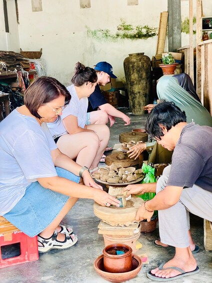 People engaged in pottery making, with clay pots and tools visible. 1