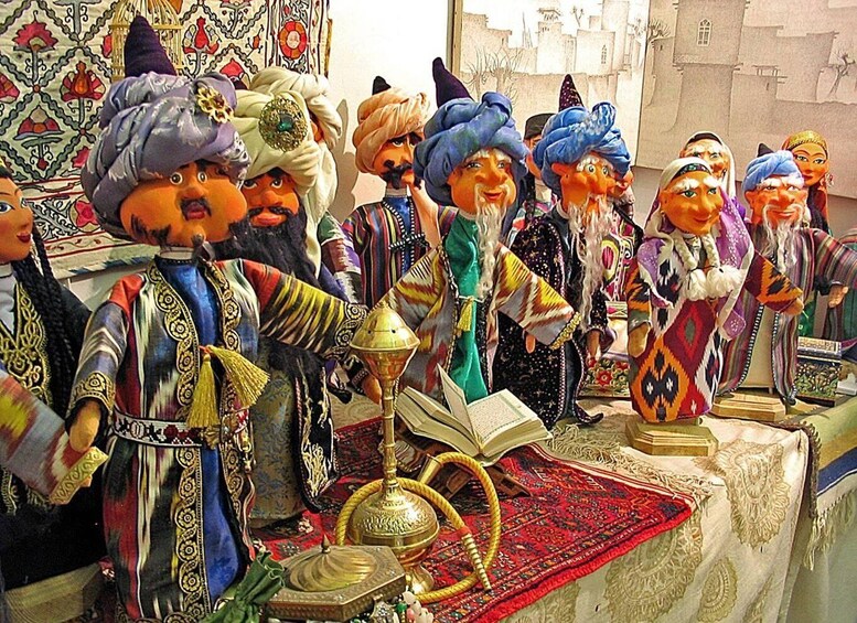 A collection of figurines dressed in traditional attire, a brass lamp, and a book on a table. 1