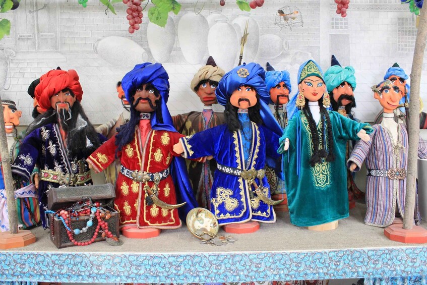 A collection of figurines in traditional attire, some with headpieces, and a chest of drawers with a globe and a bag of coins. 2