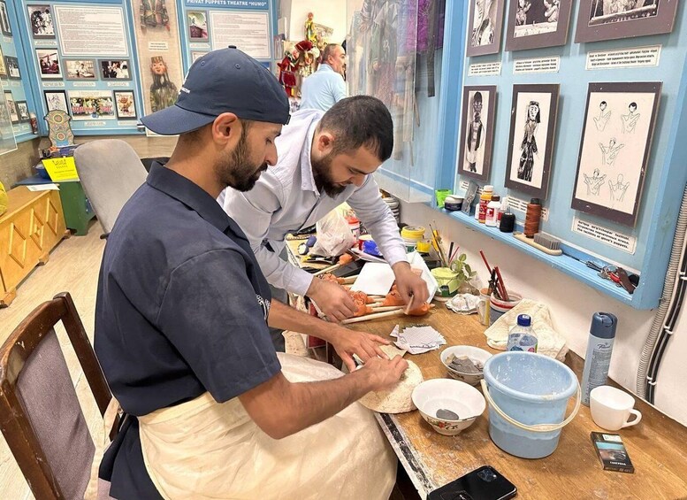 Two individuals engaged in a craft activity, surrounded by art supplies and reference materials. 4
