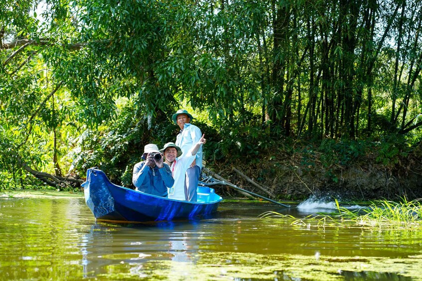 A group of people in a blue boat on a river surrounded by dense greenery. 2