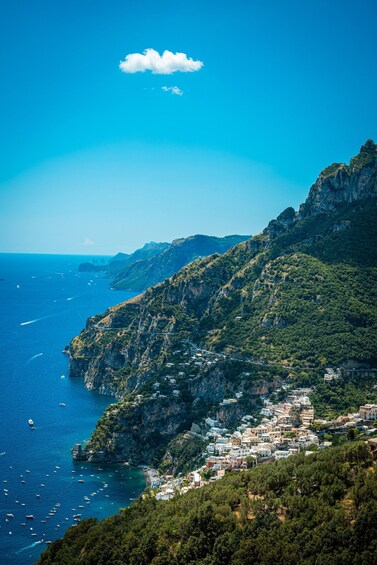 A coastal town nestled in a mountainous landscape with clear blue skies and a rainbow. 3