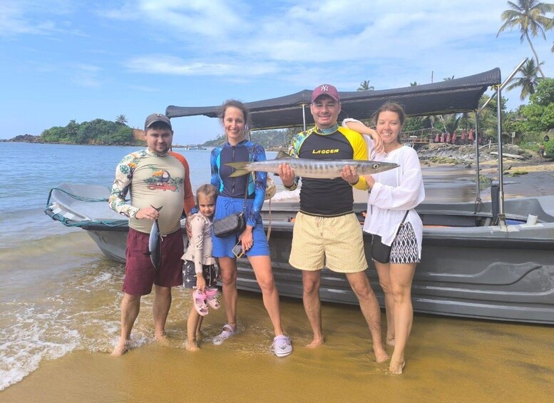 A group of people by a boat on a beach with palm trees and water in the background. 5