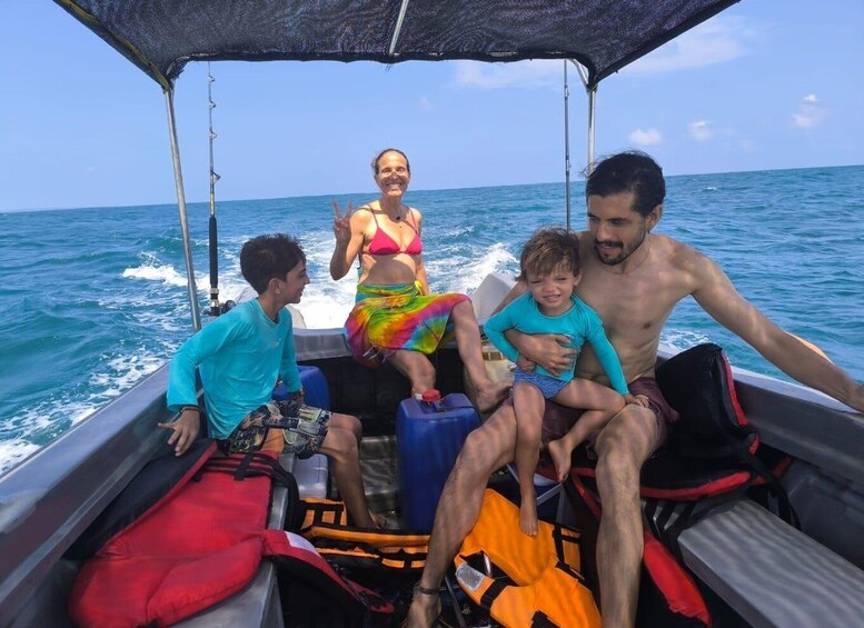 A boat with four people, including a woman in a bikini and two children, on a clear day at sea. 2