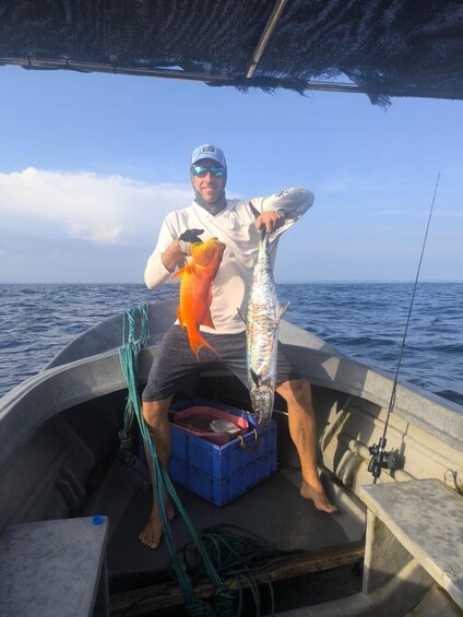 A person on a boat holding a fish and a larger fish. 3