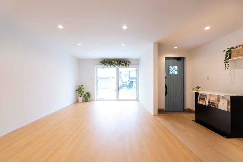 A spacious hallway with wooden flooring, a reception desk, and a door leading outside. 2