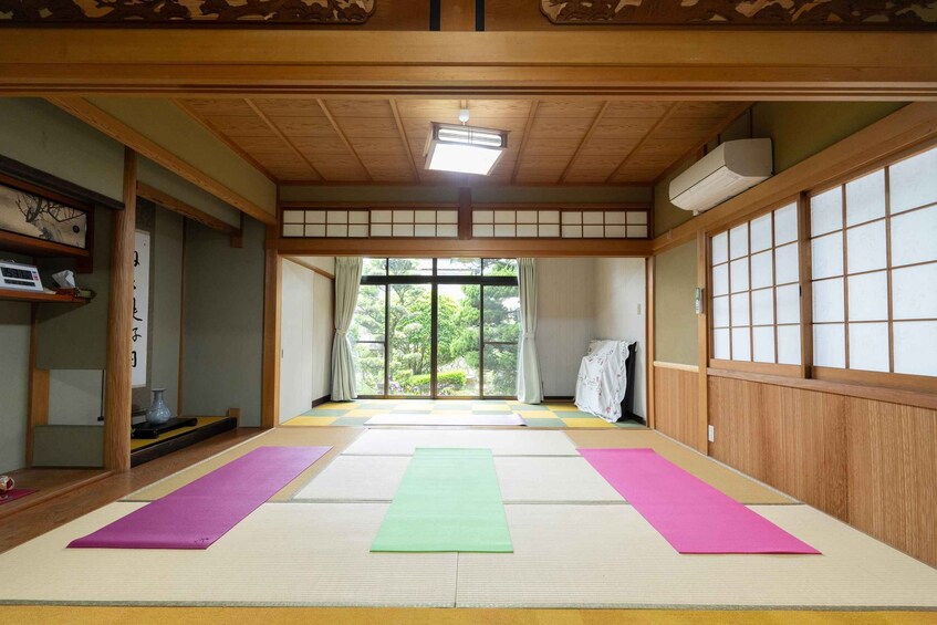 A traditional Japanese room with tatami mats, sliding doors, and a view of greenery outside. 1