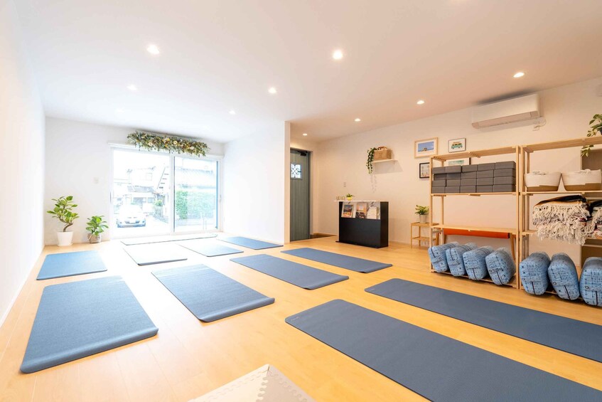 A yoga studio with mats, a reception desk, and a view of the outside. 5