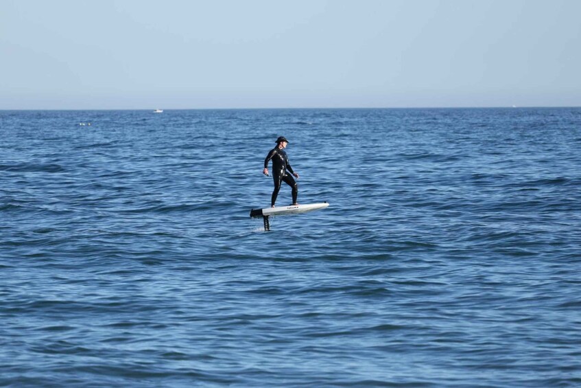 A person surfing on a white board in the ocean. 5