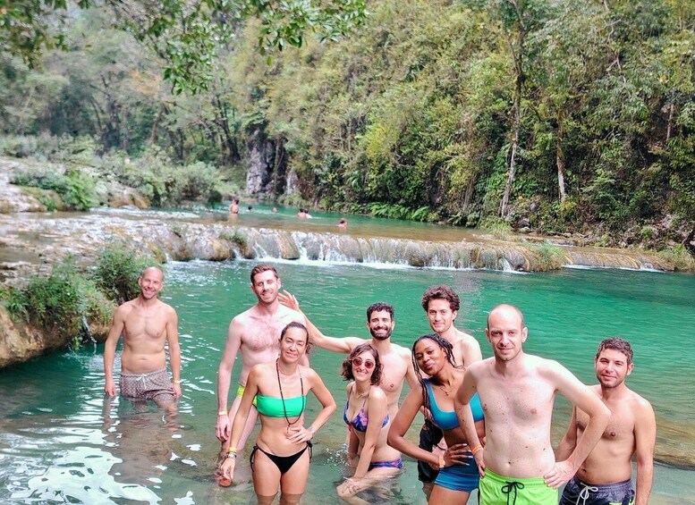 A group of people standing in a river surrounded by greenery. 5