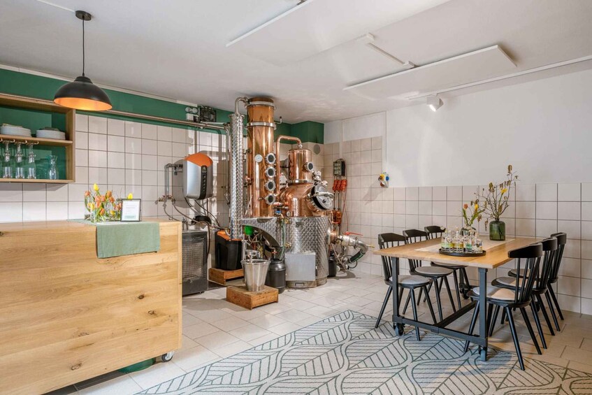 A modern kitchen with a copper distillation apparatus, a wooden counter, and a dining area with chairs. 4