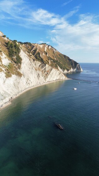 A coastal landscape with cliffs, clear blue water, and a boat. 4