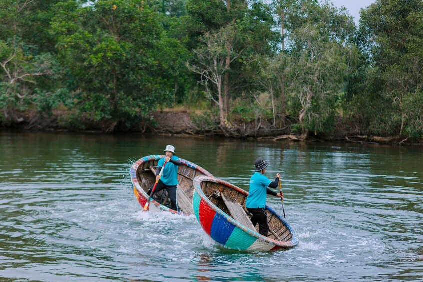Two individuals paddling a colorful boat on a calm river surrounded by dense greenery. 1