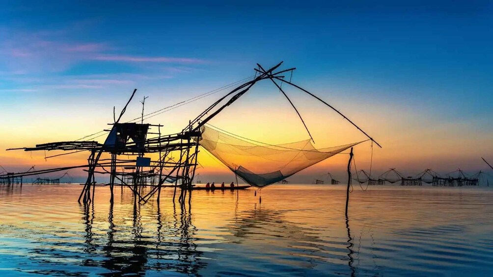 A fishing net structure over water at sunset. 2