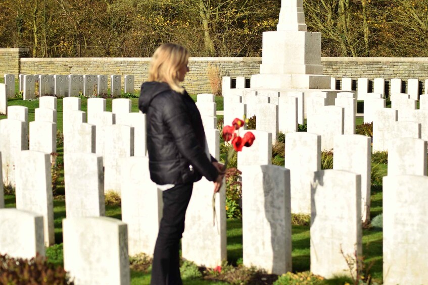 A person standing in a cemetery with white headstones and a monument. 4