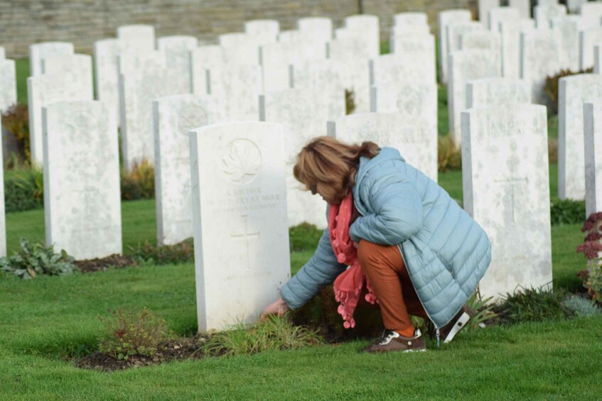 A person crouching by a gravestone in a cemetery. 5