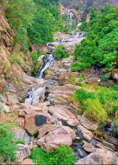A cascading waterfall surrounded by lush greenery and rocky terrain. 4