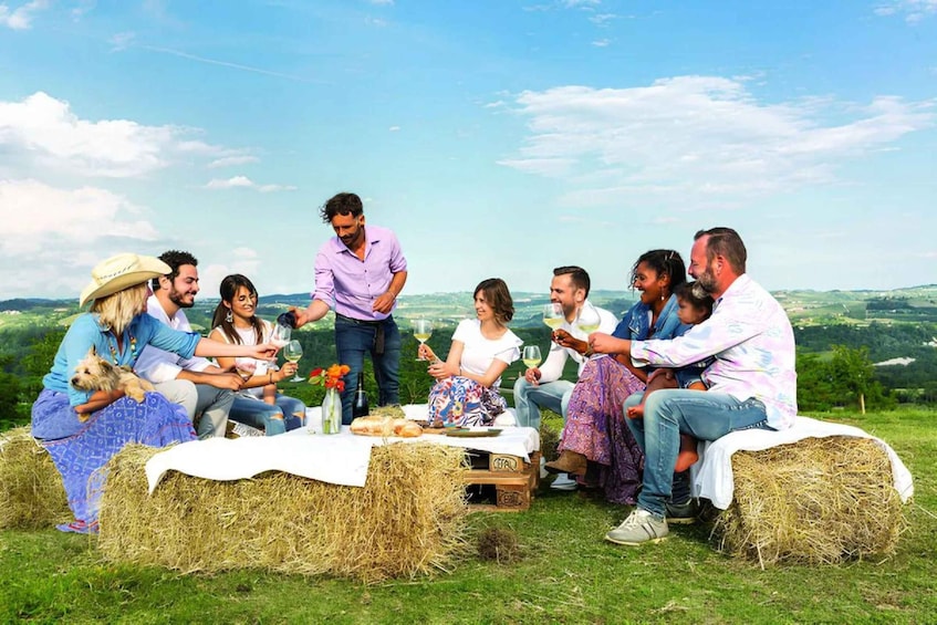 A group of people sitting on hay bales outdoors with a scenic landscape in the background. 1