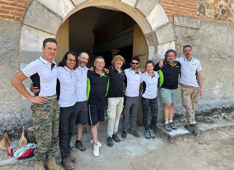 A group of people standing in front of a stone archway with a building entrance. 3