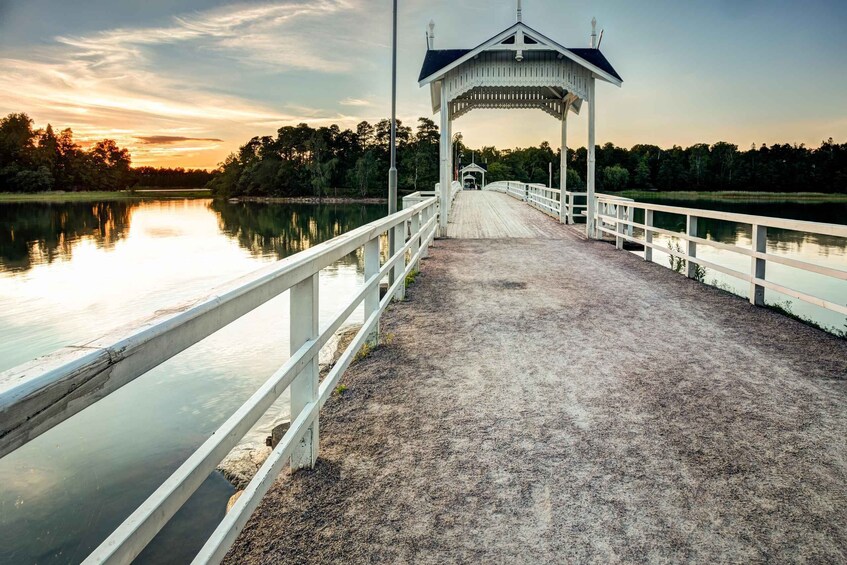 A wooden pier leading to a gazebo by a calm lake at sunset. 1