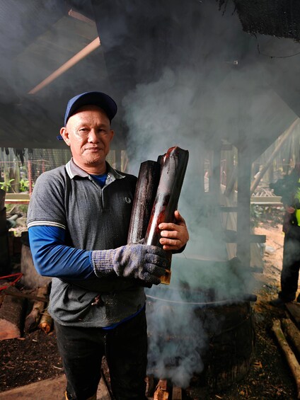 A person holding two cylindrical objects, likely pipes, with smoke in the background. 1
