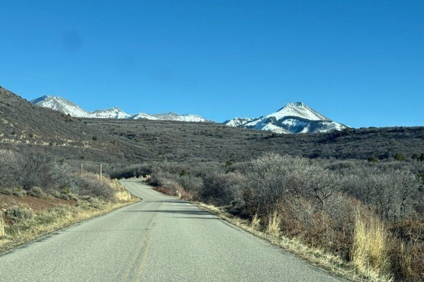 A road leading to snow-capped mountains under a clear sky. 5
