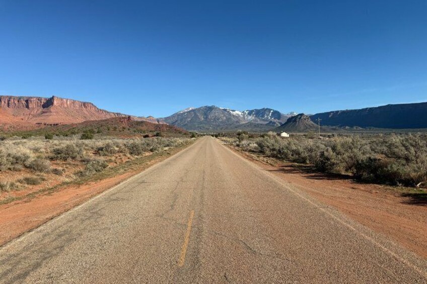 A long, straight road in a desert landscape with mountains in the distance. 4