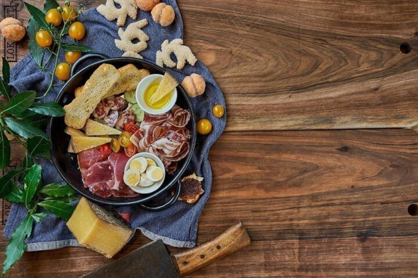 A charcuterie board with meats, cheese, eggs, and olives on a wooden table. 1