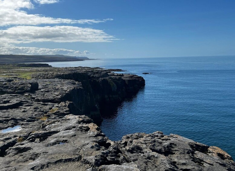 A rocky coastline with clear blue waters and distant land. 2