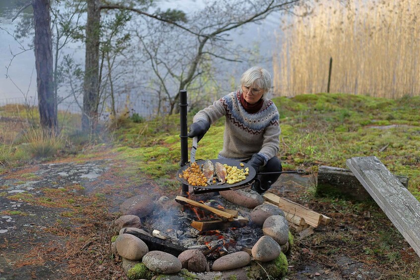 An elderly person cooking outdoors with a grill over an open fire. 3