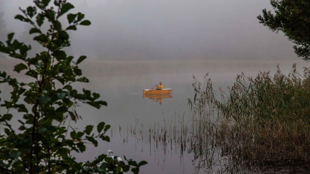 A calm lake with a small boat and reeds in the foreground. 4