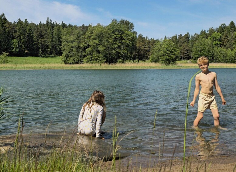 Two children playing in a lake surrounded by trees. 5